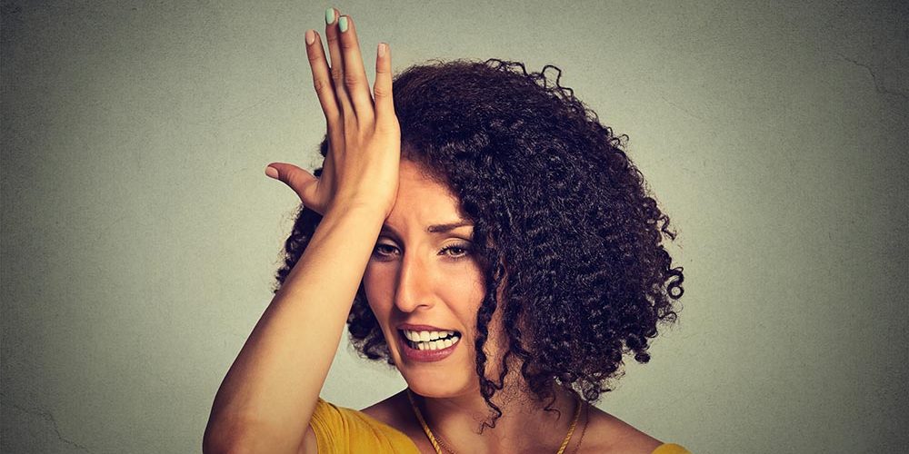 middle age woman slapping hand on head to say duh made mistake What not to do before you buy your next home